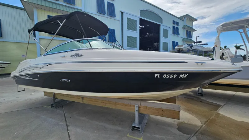 Slide: The Image of 2005 Sea Ray 220 Sundeck boat with black hull, docked outdoors. - 5