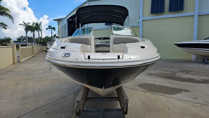 Slide: The Image of 2005 Sea Ray 220 Sundeck boat on a trailer, parked outdoors near a building. - 6