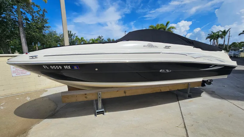 Slide: The Image of 2005 Sea Ray 220 Sundeck boat on a trailer, parked outdoors under a blue sky. - 7