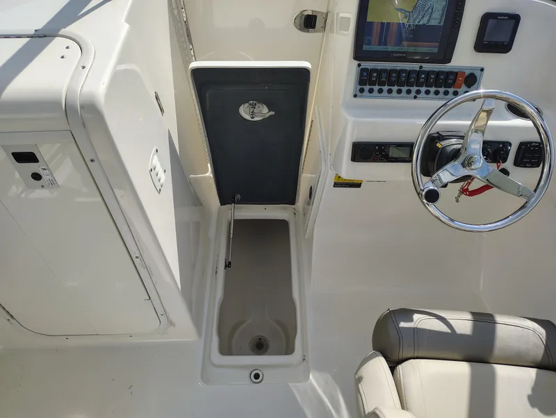 Slide: The Image of 2023 Key West 239 DFS boat cockpit with steering wheel, control panel, and storage compartment. - 14