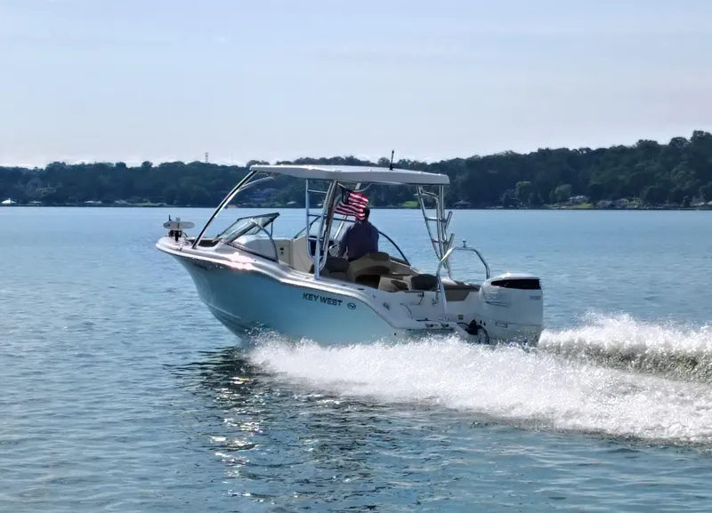 Slide: The Image of 2023 Key West 239 DFS boat cruising on a serene lake with an American flag. - 32