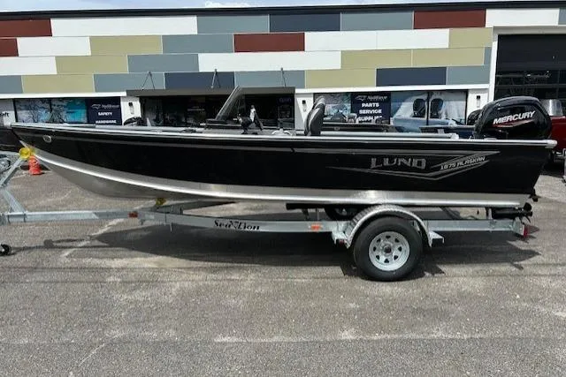 The Image of 2025 Lund 1875 Alaskan SS boat on trailer, parked outside a building. - 0