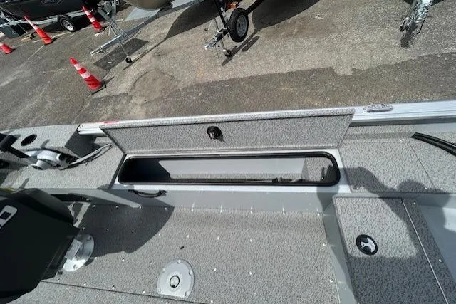 Slide: The Image of 2025 Lund 1875 Alaskan SS boat interior with open storage compartment on textured flooring. - 11