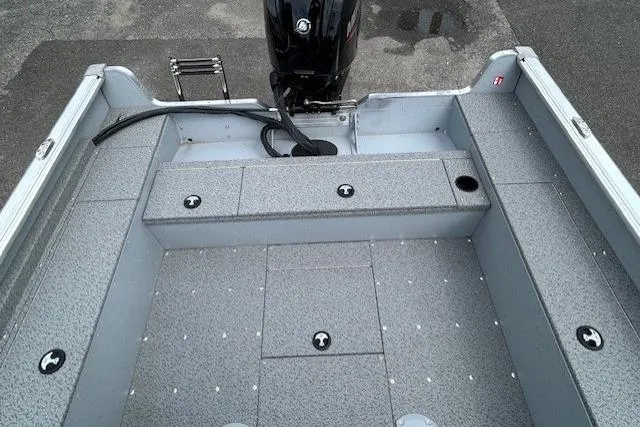 Slide: The Image of 2025 Lund 1875 Alaskan SS boat interior with motor, gray flooring, and storage compartments. - 8