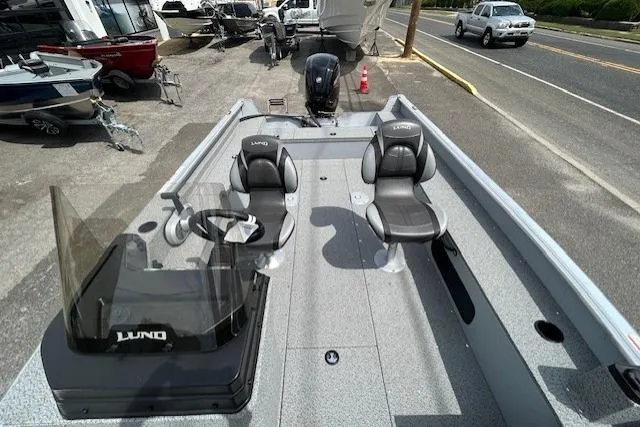 Slide: The Image of 2025 Lund 1875 Alaskan SS boat with dual seats and steering console, parked on roadside. - 9