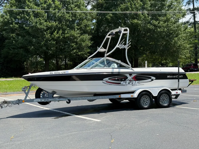 Slide: The Image of 2001 MasterCraft X-Star boat on trailer in parking lot, surrounded by trees. - 19