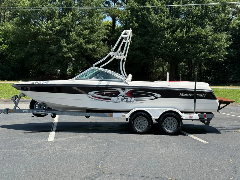 Slide: The Image of 2001 MasterCraft X-Star boat on trailer, parked outdoors with trees in background. - 20