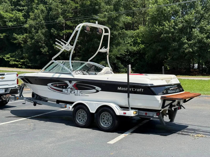Slide: The Image of 2001 MasterCraft X-Star boat on trailer in parking lot, surrounded by trees. - 21