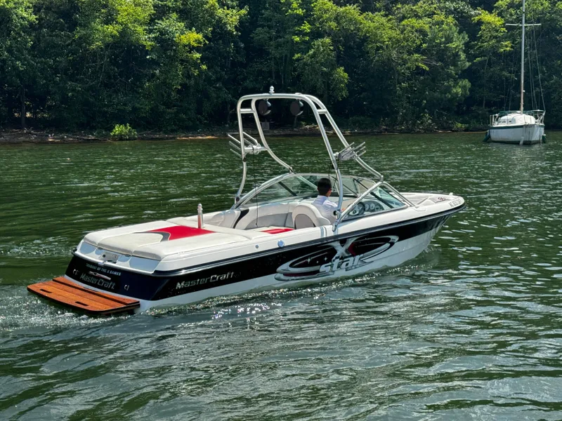 Slide: The Image of 2001 MasterCraft X-Star boat cruising on a lake with lush green trees. - 3