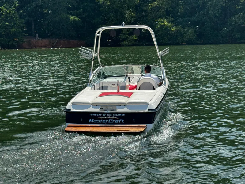 Slide: The Image of 2001 MasterCraft X-Star boat cruising on a serene lake with lush green surroundings. - 4