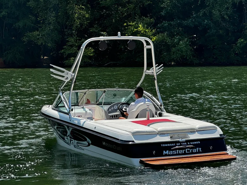 Slide: The Image of 2001 MasterCraft X-Star boat cruising on a serene lake with lush green trees. - 5