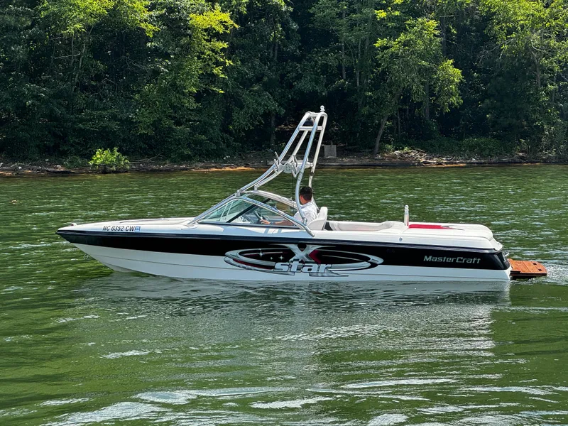 Slide: The Image of 2001 MasterCraft X-Star boat on a lake with lush green forest background. - 6