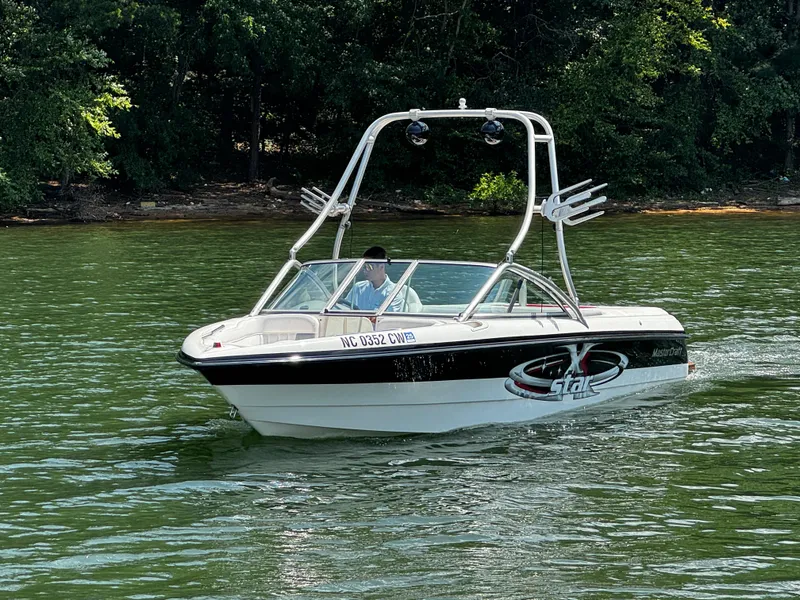 Slide: The Image of 2001 MasterCraft X-Star boat cruising on a lake with lush green trees in the background. - 8