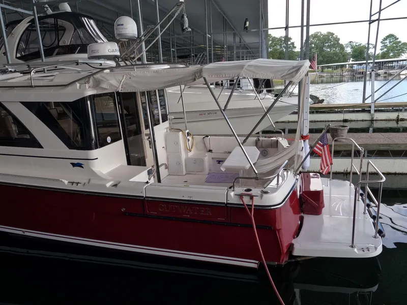 Slide: The Image of 2020 Cutwater C-30 Sedan docked under a covered marina, featuring a red hull and American flag. - 4
