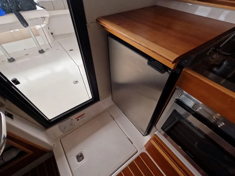 Slide: The Image of 2020 Cutwater C-30 Sedan interior with compact kitchen, featuring fridge and microwave. - 47