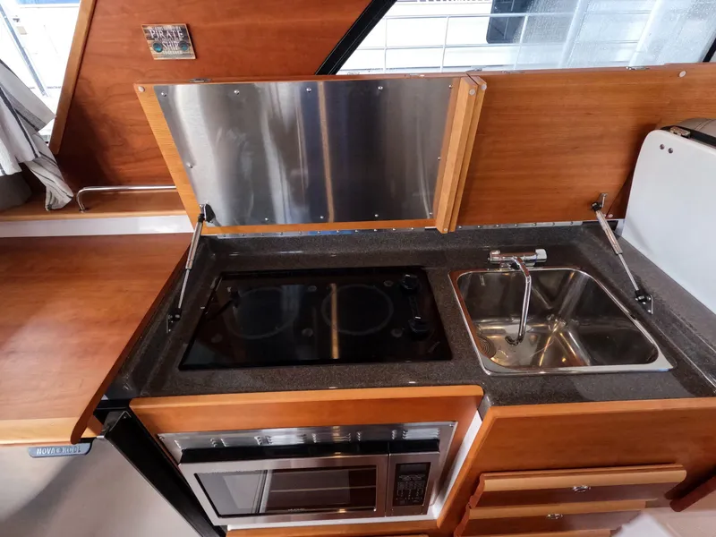 Slide: The Image of 2020 Cutwater C-30 Sedan kitchen with stove, sink, and microwave in a compact layout. - 48