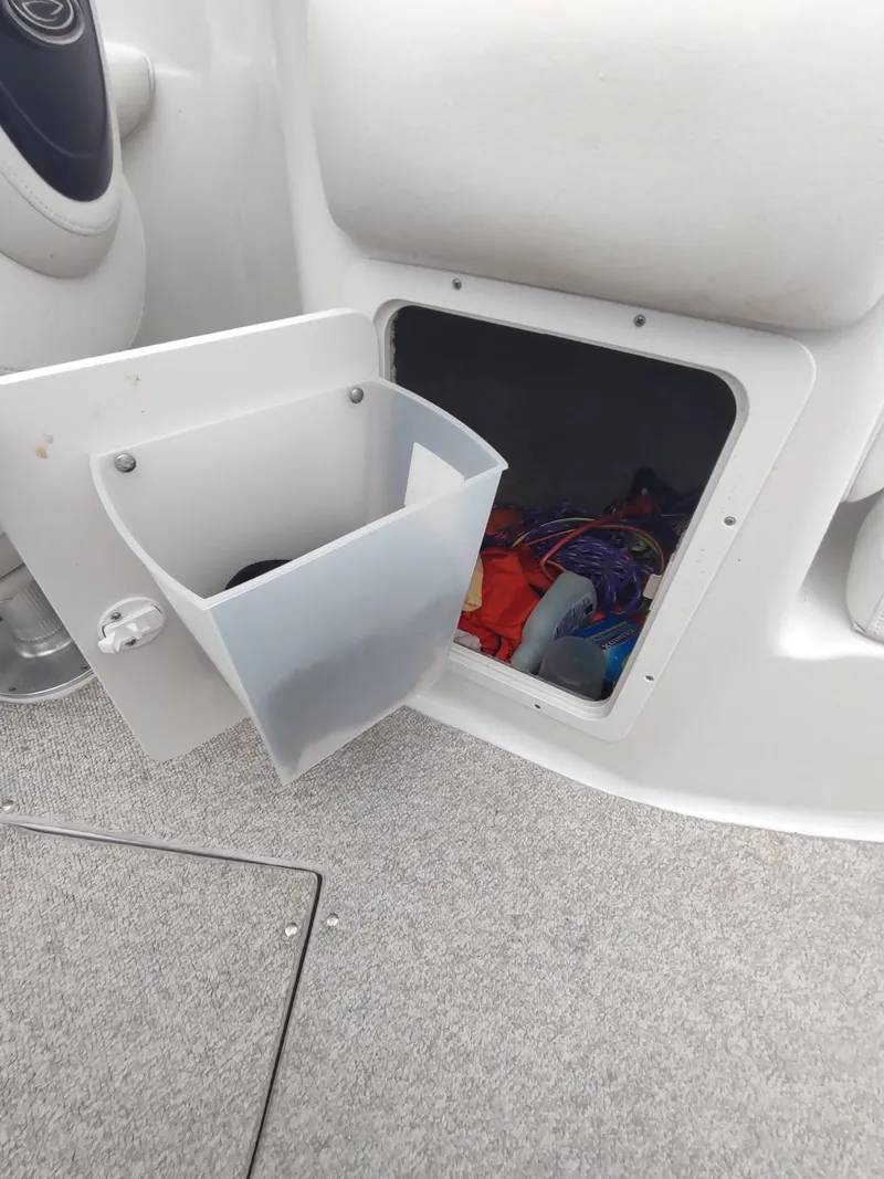 Slide: The Image of Open storage compartment on 2005 Crownline 270 BR boat, showing interior items and carpeted floor. - 12