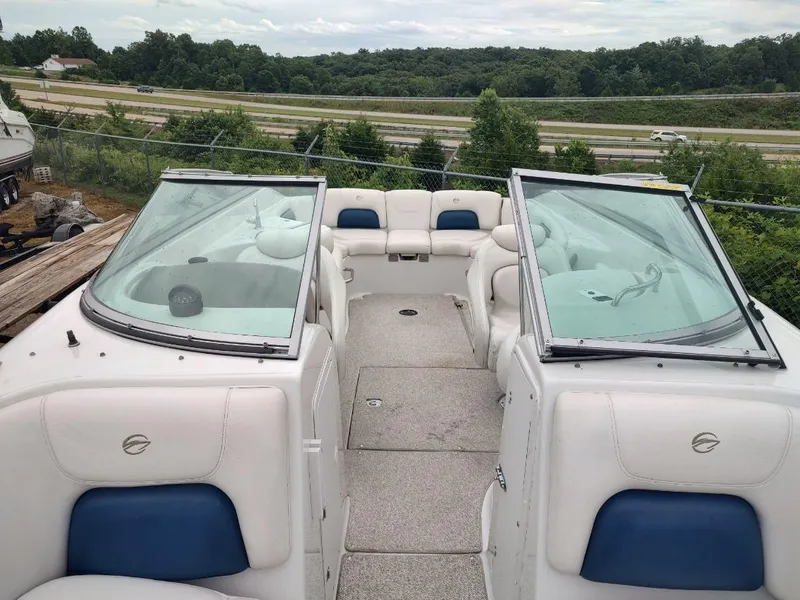 Slide: The Image of 2005 Crownline 270 BR boat with white and blue seating, parked near a highway. - 33