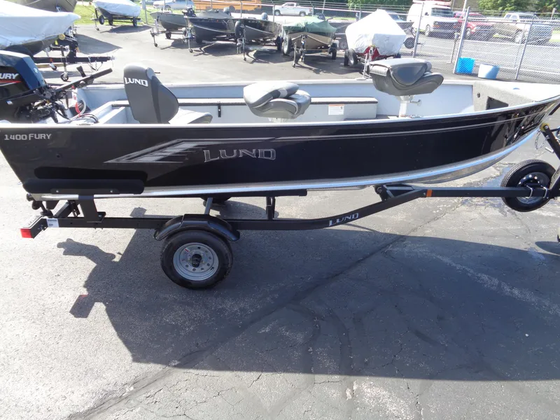Slide: The Image of 2025 Lund 1400 Fury Tiller boat on trailer, parked outdoors. - 2