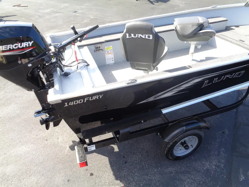 Slide: The Image of 2025 Lund 1400 Fury Tiller boat with Mercury engine on trailer, outdoor setting. - 3