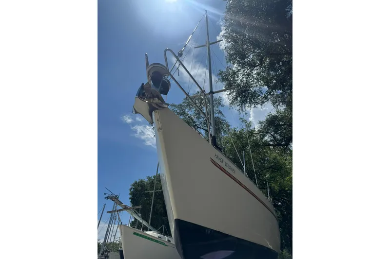 Slide: The Image of Sailboat Maxi 35 CC from 1990 under bright sunlight, surrounded by trees. - 15