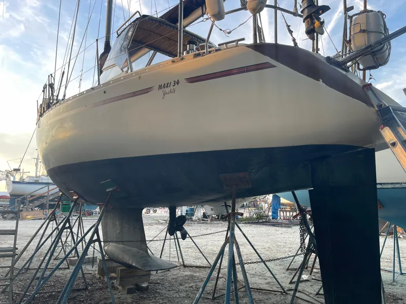 Slide: The Image of 1990 Maxi 35 CC sailboat on stands in a boatyard, under a clear sky. - 23
