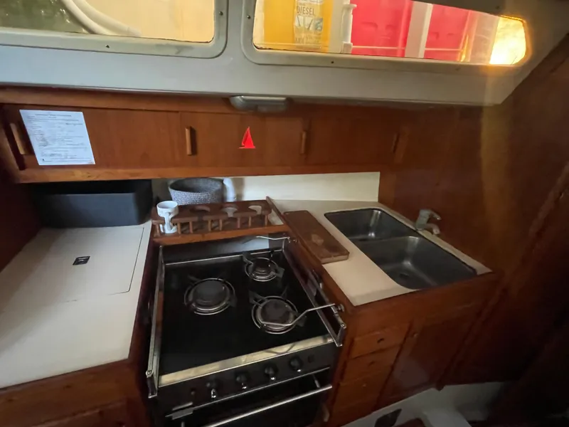 Slide: The Image of Compact kitchen in a 1990 Maxi 35 CC sailboat with stove, sink, and wooden cabinetry. - 42