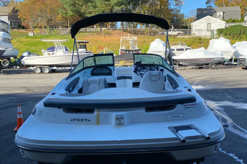 Slide: The Image of 2013 Sea Ray 205 Sport boat in a marina, rear view with canopy. - 2