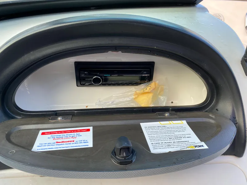 Slide: The Image of 2013 Sea Ray 205 Sport dashboard compartment with stereo system and safety labels. - 7