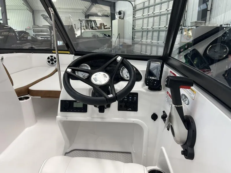 Slide: The Image of 2026 Stingray 191 DC boat interior with white seating and modern dashboard in a showroom. - 8