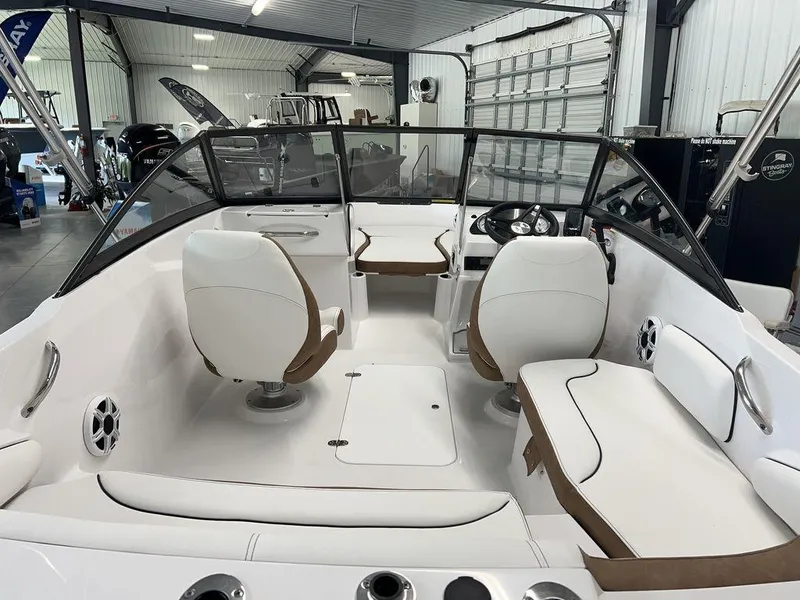Slide: The Image of 2026 Stingray 191 DC boat interior with white and brown seating, displayed in a showroom. - 9