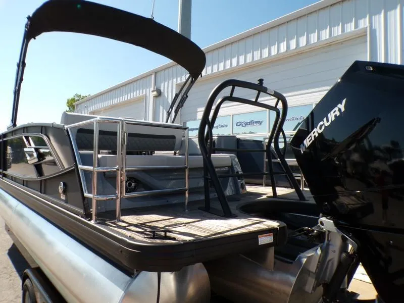 Slide: The Image of 2025 Godfrey AquaPatio 255 SFL pontoon boat with Mercury engine, docked outdoors. - 19