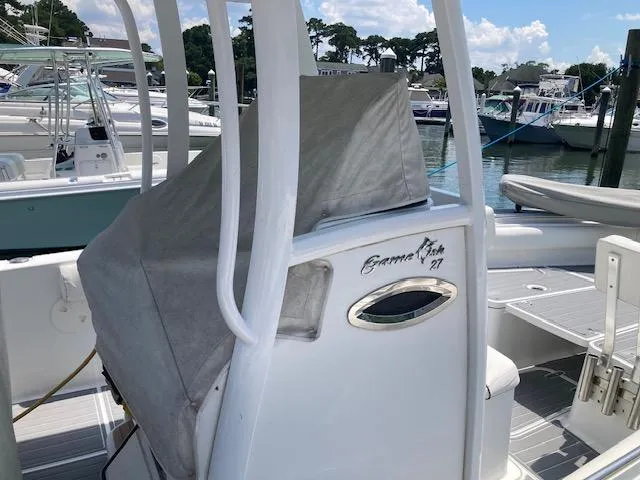 Slide: The Image of 2014 Sea Hunt Gamefish 27 boat docked, featuring covered seating and sleek design. - 9