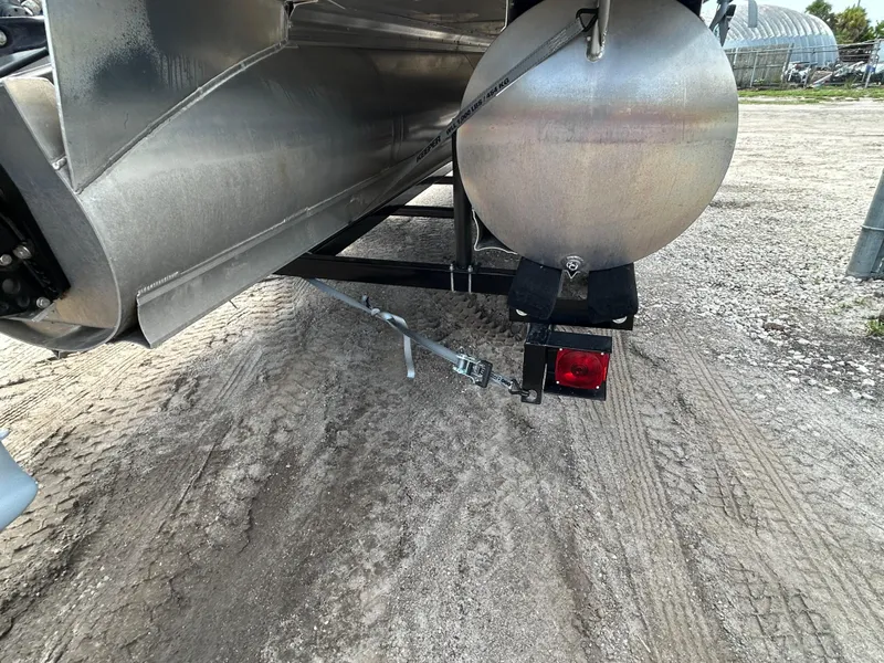 Slide: The Image of 2024 Tahoe Pontoon 2385 TZ trailer hitch and rear view on dirt surface. - 11