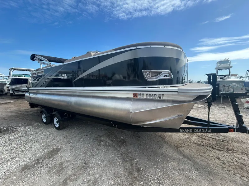 Slide: The Image of 2024 Tahoe Pontoon 2385 TZ on trailer, sleek design, parked outdoors under blue sky. - 12