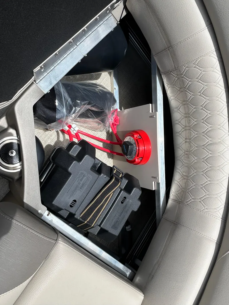 Slide: The Image of 2024 Tahoe Pontoon 2385 TZ interior storage compartment with battery and red switch. - 24