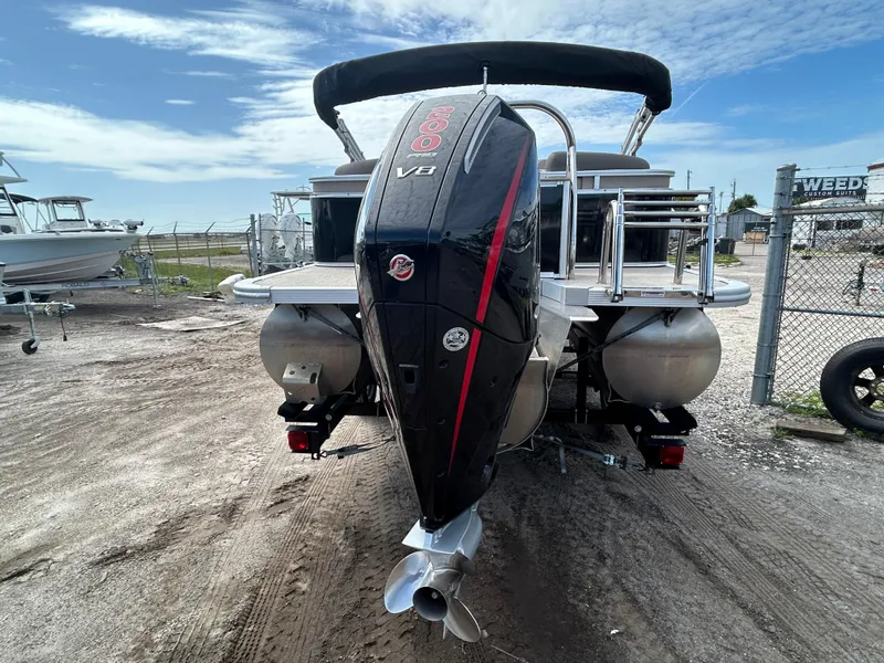 Slide: The Image of 2024 Tahoe Pontoon 2385 TZ with powerful outboard motor, parked on gravel lot. - 4