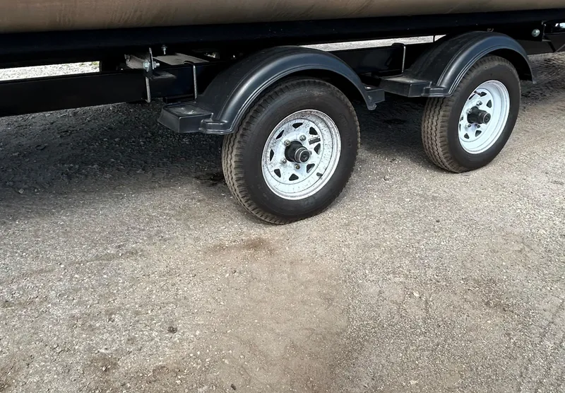 Slide: The Image of Trailer wheels of a 2024 Tahoe Pontoon 2385 TZ on gravel surface. - 9