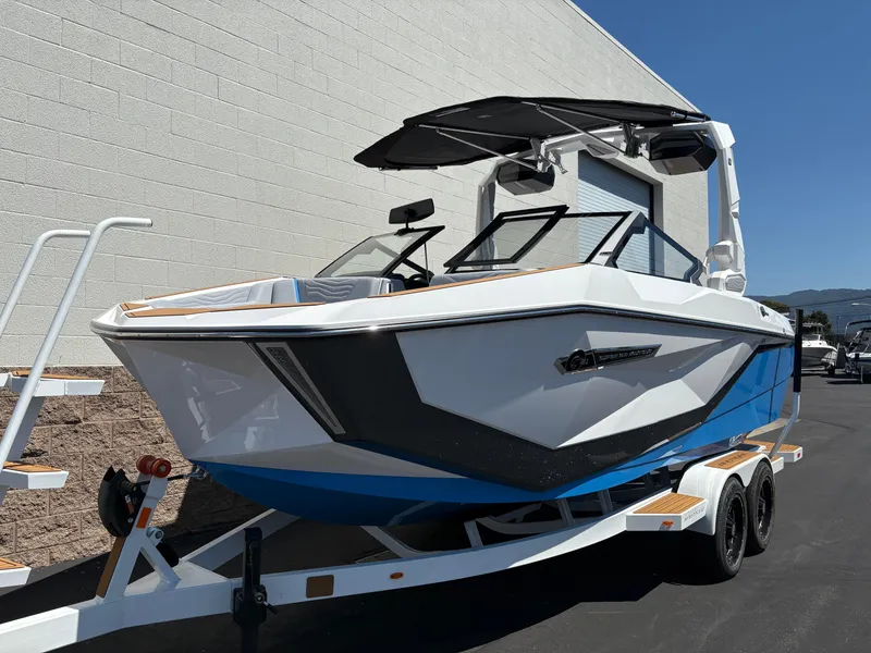 Slide: The Image of 2026 Nautique Super Air Nautique G21 boat on trailer, white and blue design. - 2