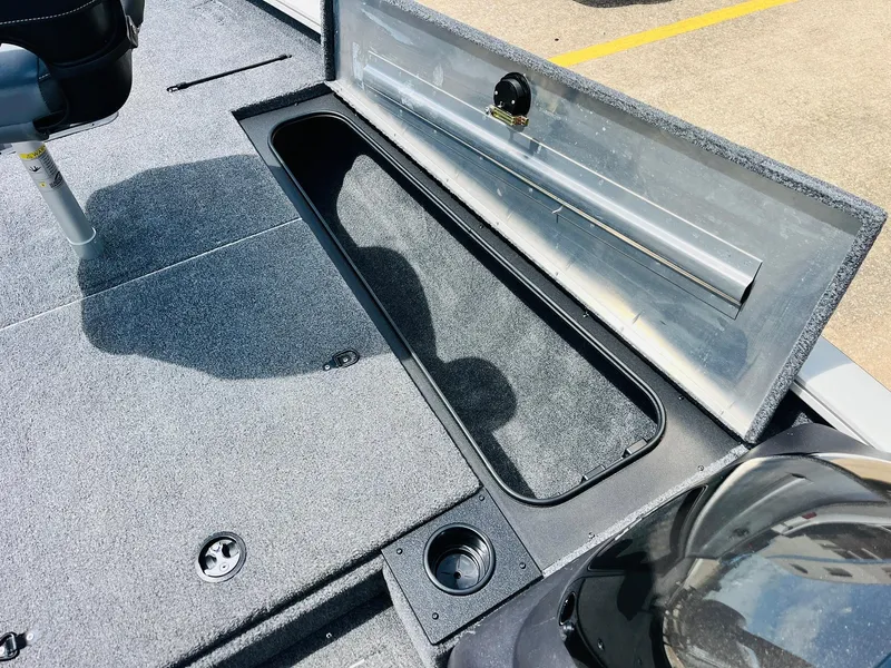 Slide: The Image of 2024 Tracker Pro Team 175 TXW boat with open storage compartment and carpeted deck. - 16