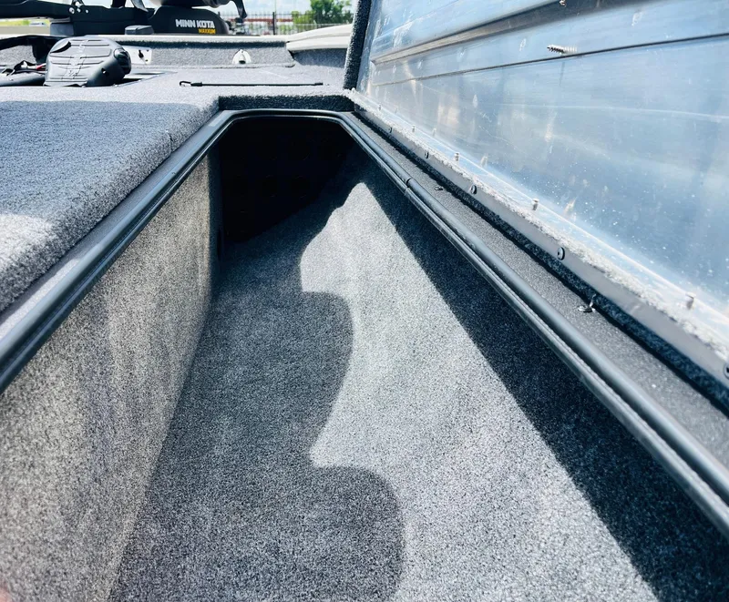 Slide: The Image of 2024 Tracker Pro Team 175 TXW boat storage compartment, carpeted interior, open lid view. - 17