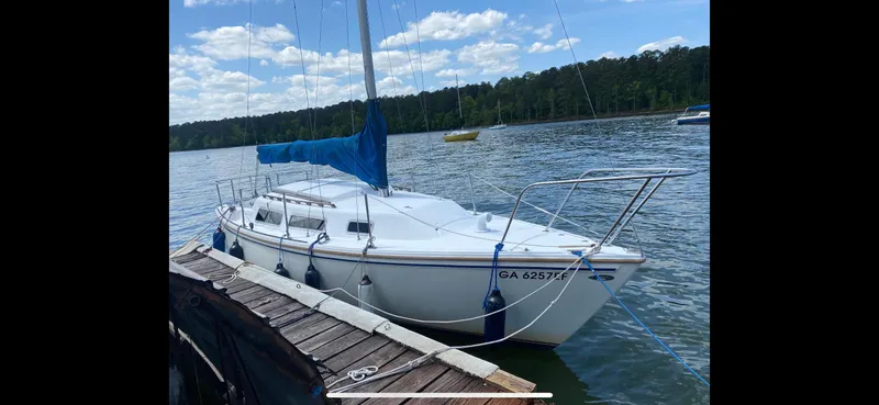 The Image of 1983 Catalina 25 sailboat docked on a serene lake under a partly cloudy sky. - 0