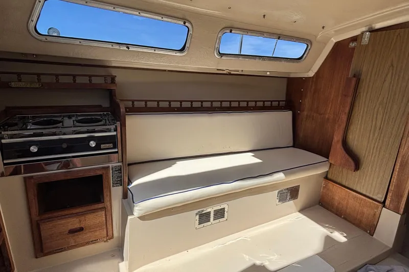 Slide: The Image of Interior of a 1983 Catalina 25 sailboat with stove and cushioned seating. - 11