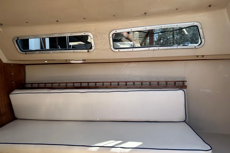 Slide: The Image of Interior of a 1983 Catalina 25 sailboat with cushioned seating and windows. - 15