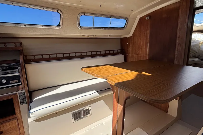 Slide: The Image of Interior of a 1983 Catalina 25 sailboat with wooden table and cushioned seating. - 19