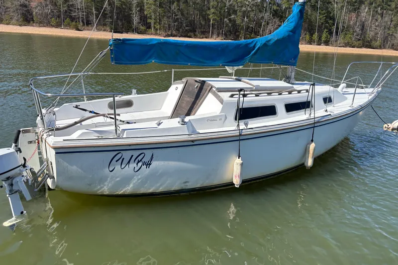 Slide: The Image of 1983 Catalina 25 sailboat with blue sail cover on calm lake water. - 28