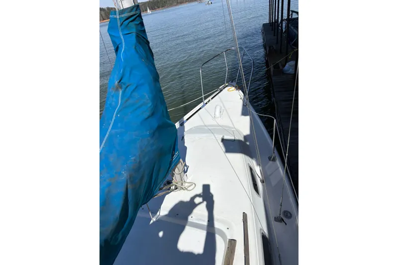 Slide: The Image of 1983 Catalina 25 sailboat with blue sail cover, docked on calm water. - 29
