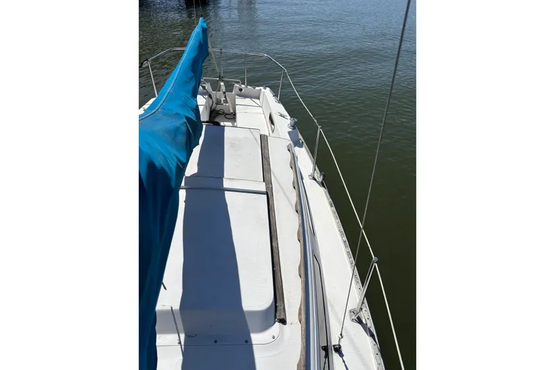 Slide: The Image of 1983 Catalina 25 sailboat deck with blue sail cover on calm water. - 30