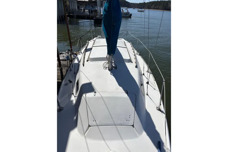 Slide: The Image of 1983 Catalina 25 sailboat docked on calm water, featuring a clean white deck. - 31