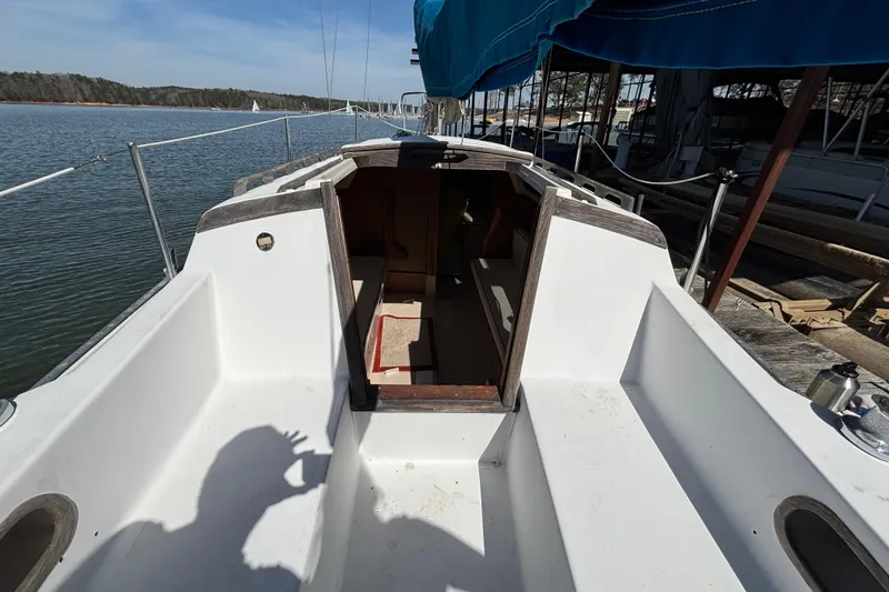 Slide: The Image of 1983 Catalina 25 sailboat cockpit with open cabin, docked by calm waters. - 32